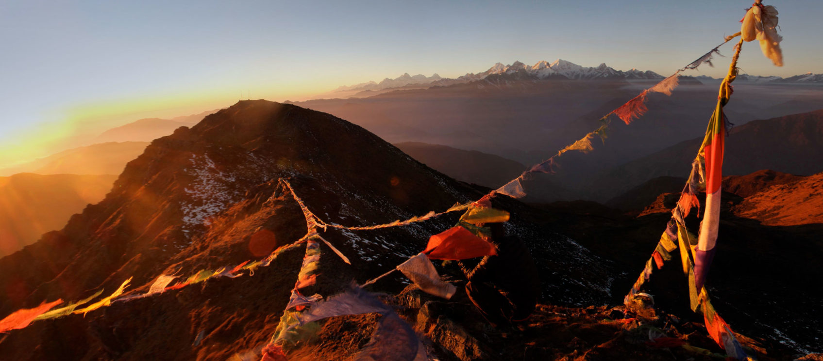 Tibetan flags on a mountain during sunset