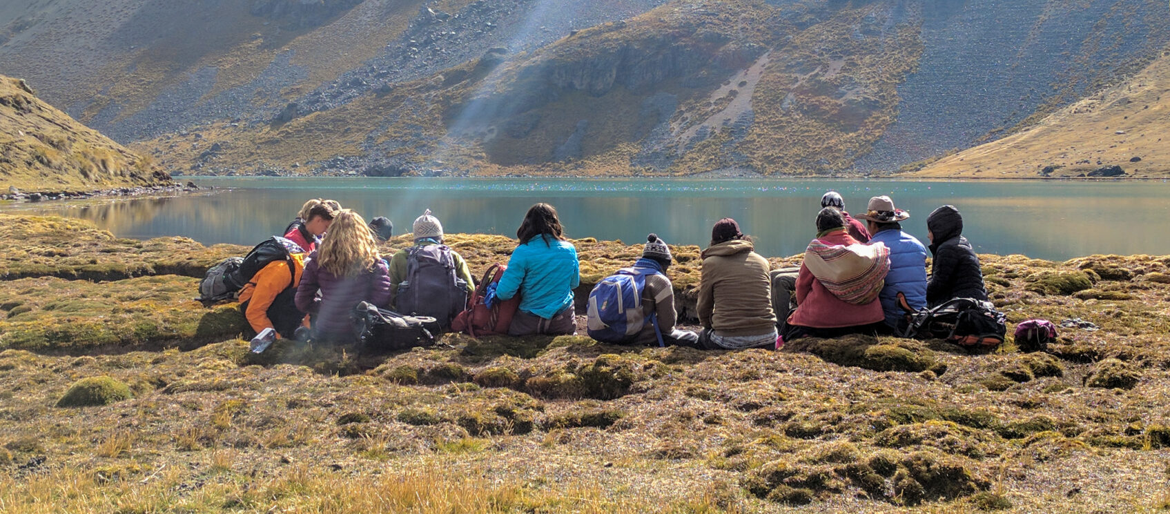 group sitting by lake in Peruvian mountains