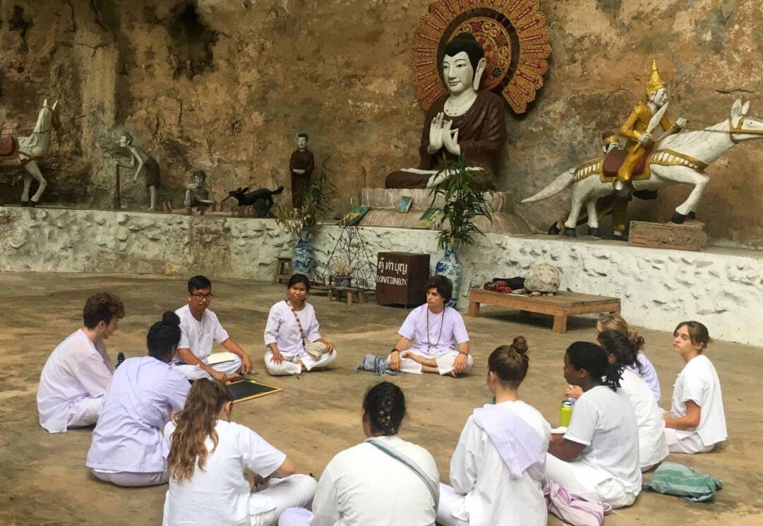 group of students dressed in white sitting in a circle on the ground
