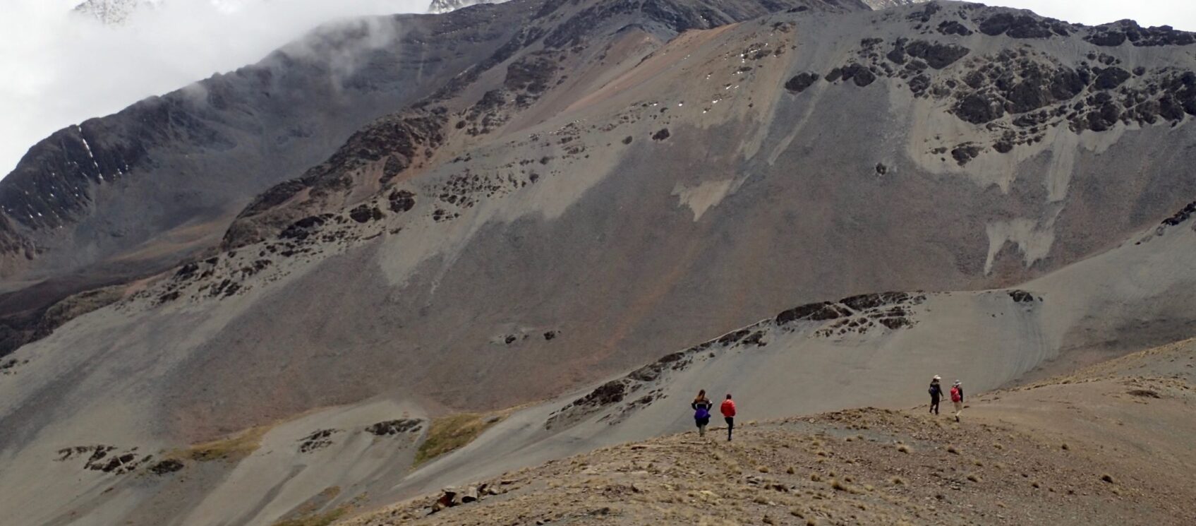 people hiking in brown mountains away from camera